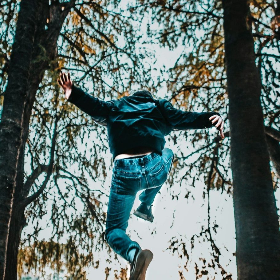 Partys und Events Person springt zwischen hohen Bäumen in einem natürlichen Umfeld.